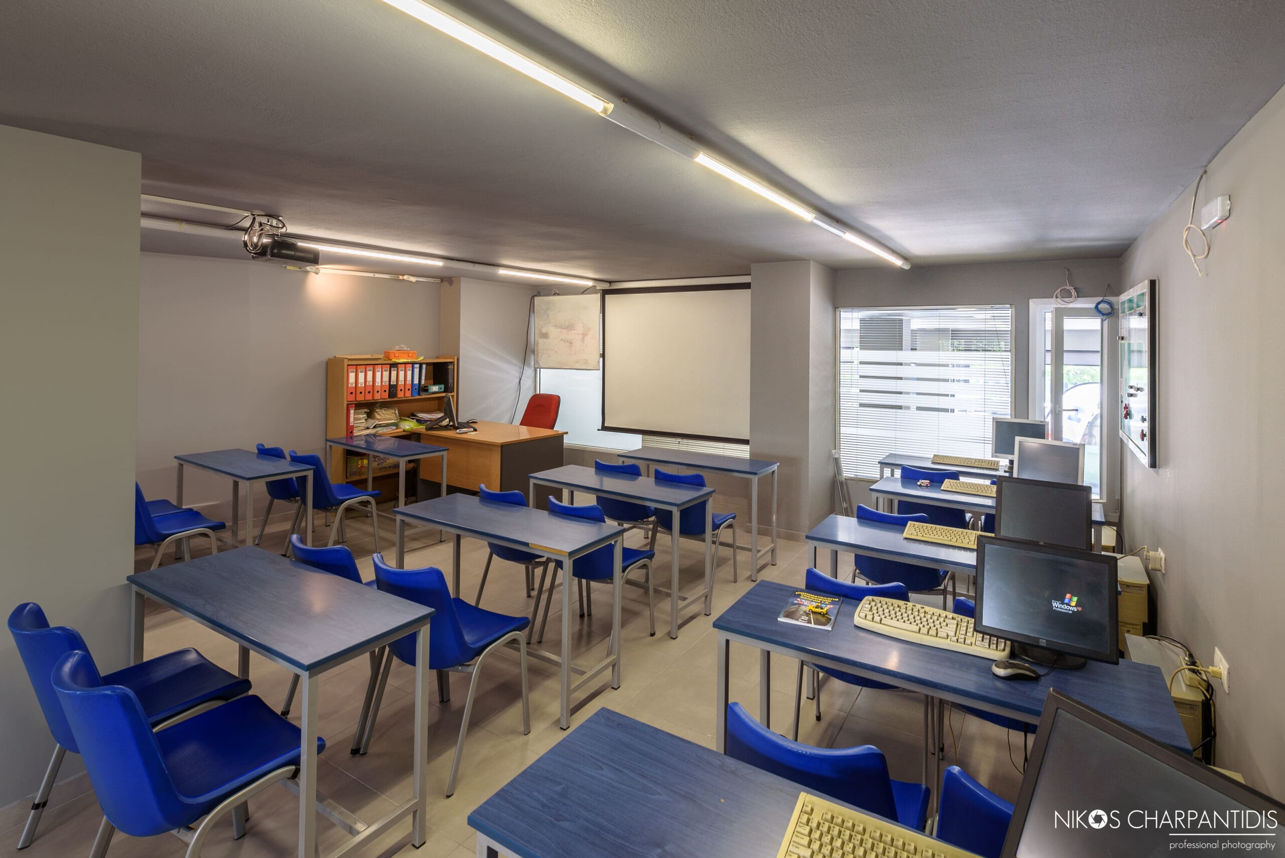 Αίθουσα θεωρητικής εκπαίδευσης με θρανία και μπλε καθίσματα
